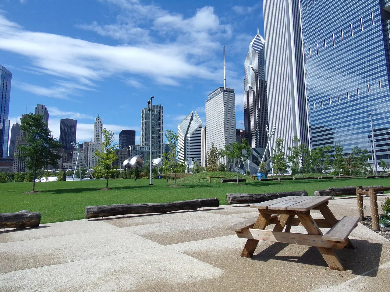 Green lawns, public paths and Chicago’s skyline at Millennium Park in bright daylight.