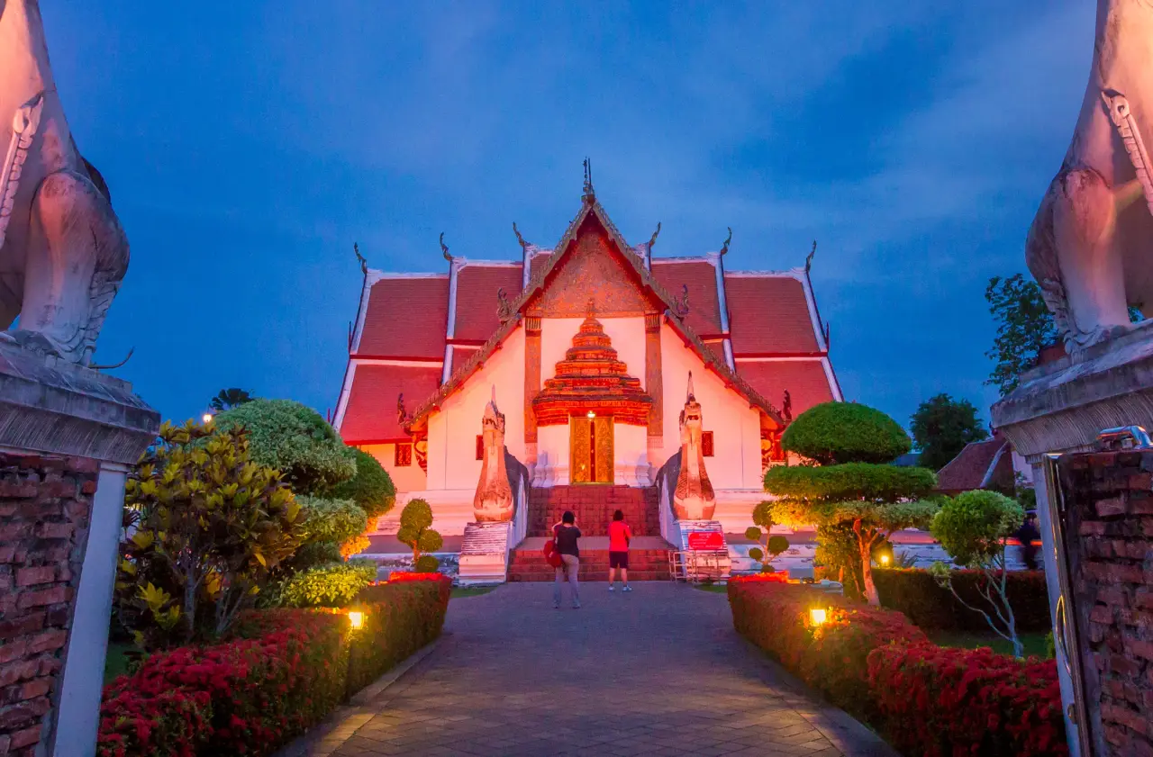 Wat Phumin illuminated at blue hour, with visitors beside the temple in Nan.