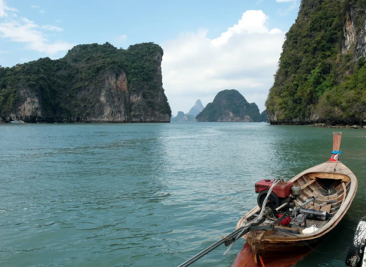 A longtail boat beside limestone cliffs at Hong Island in Krabi