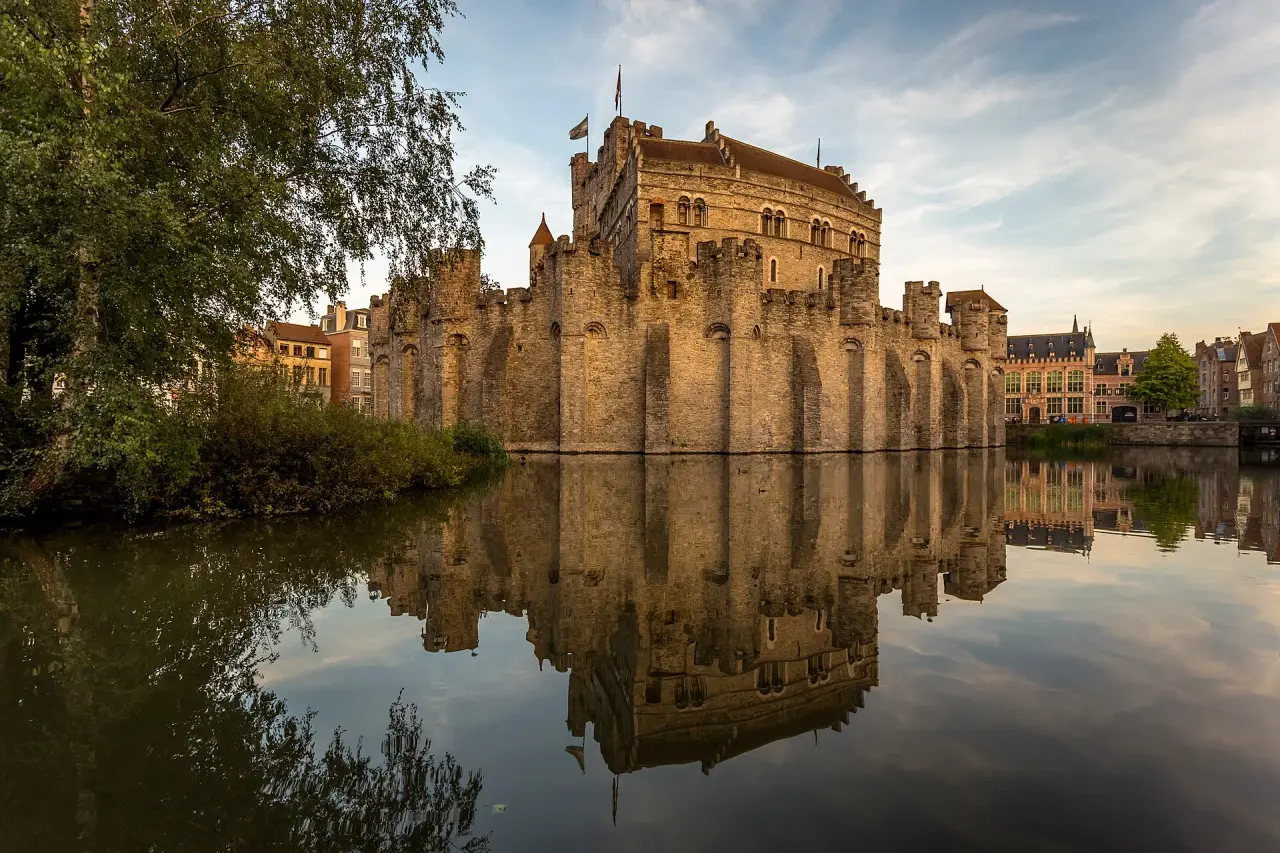 Gravensteen castle reflected in still water in warm evening daylight