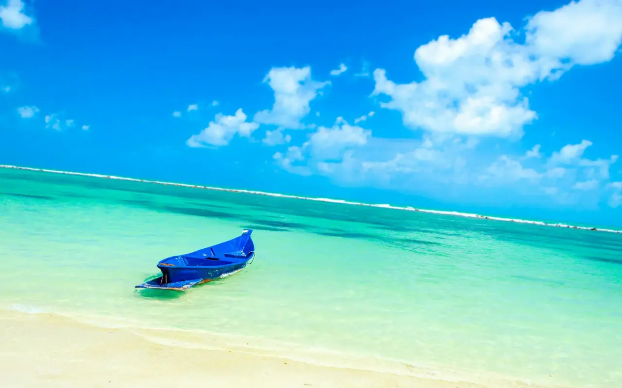 Ein blaues Longtailboot im klaren türkisfarbenen Flachwasser vor Koh Samui
