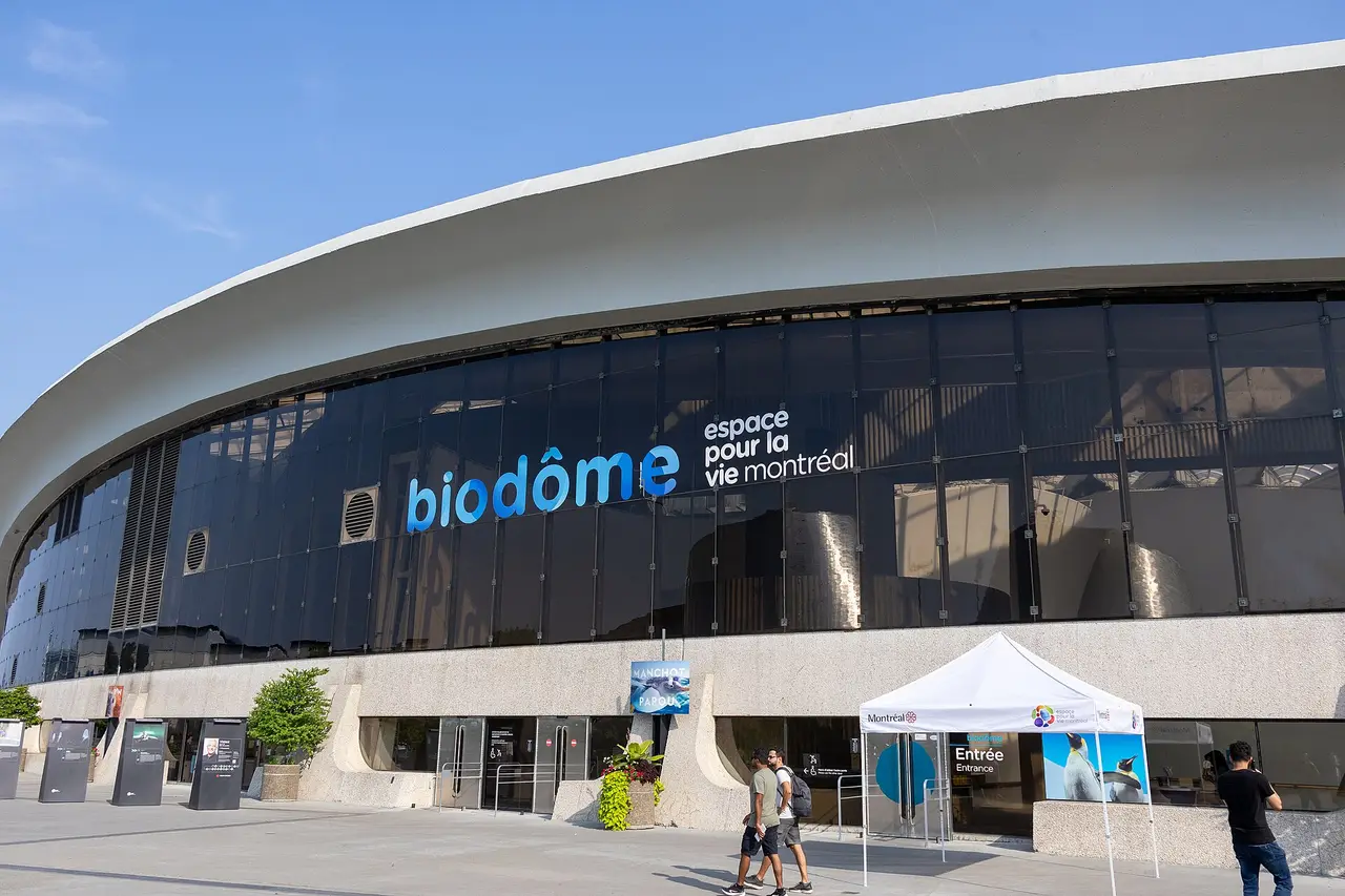 Das geschwungene Dach und der signierte Glaseingang von Montréal Biodôme bei klarem Sommertagslicht