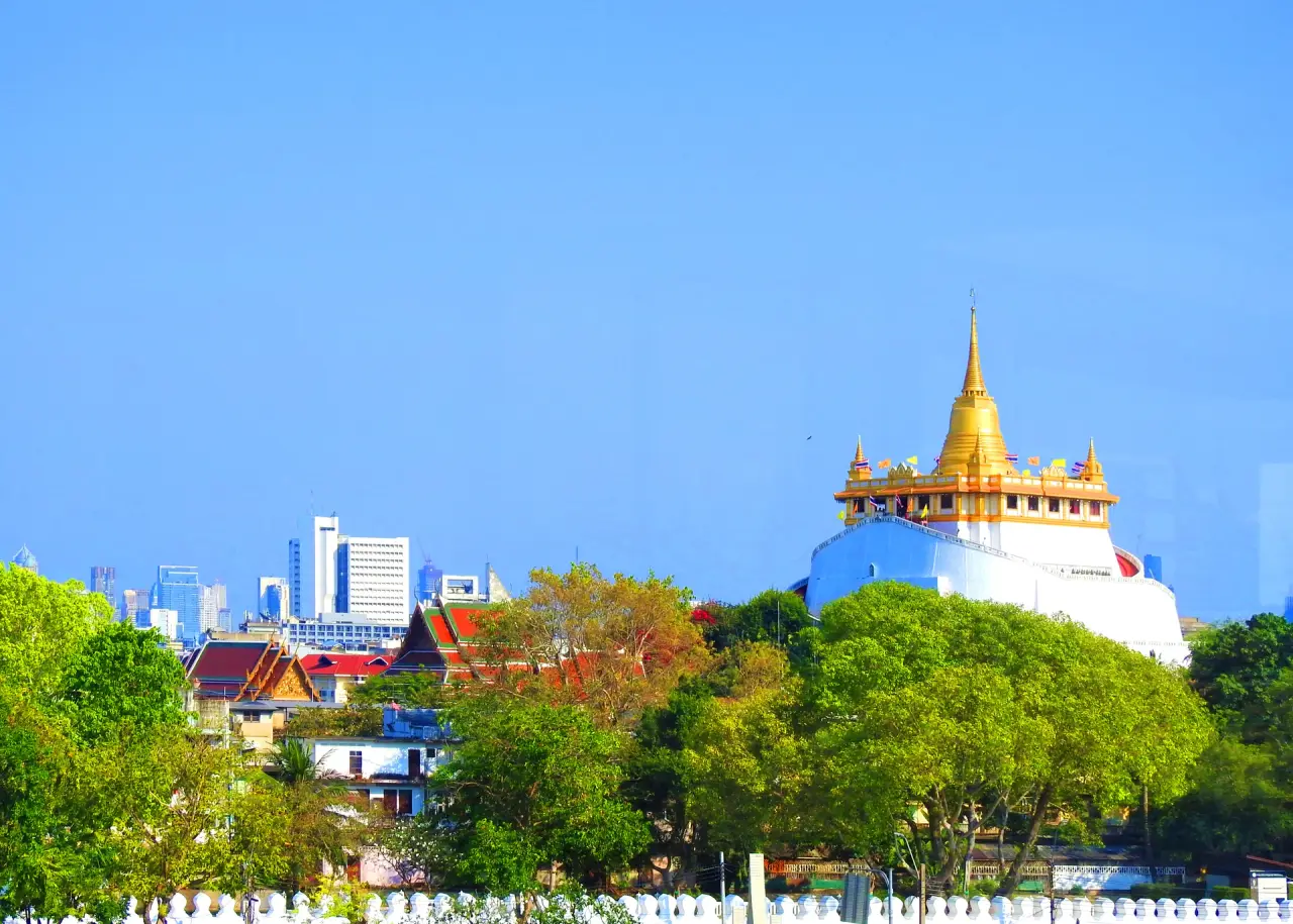 Golden Mount of Wat Saket rising above green trees and Bangkok roofs