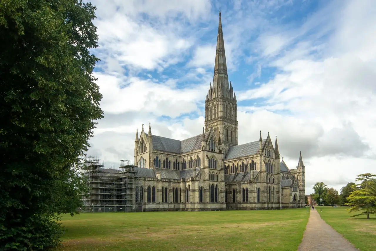 La aguja de la catedral de Salisbury y la piedra gótica bajo un cielo azul y blanco brillante