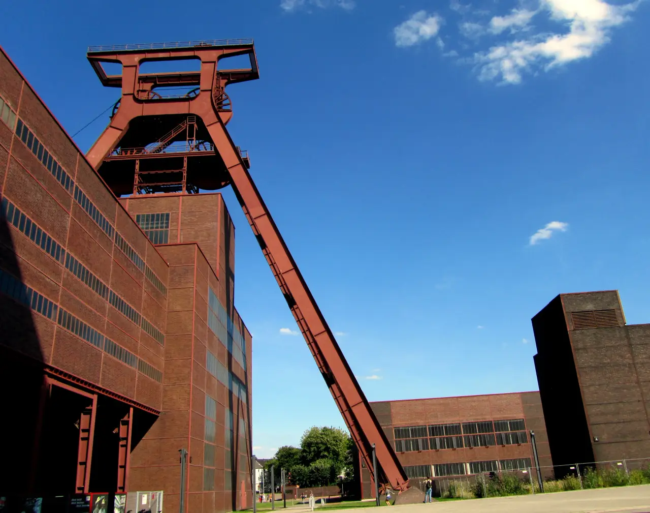 Le chevalement en acier rouge et les bâtiments industriels en briques de Zollverein, à Essen, sous un ciel bleu.