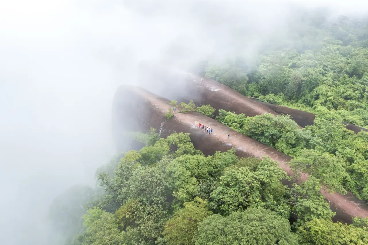 Visitors on the broad sandstone rocks of Hin Sam Wan amid green forest and mist.