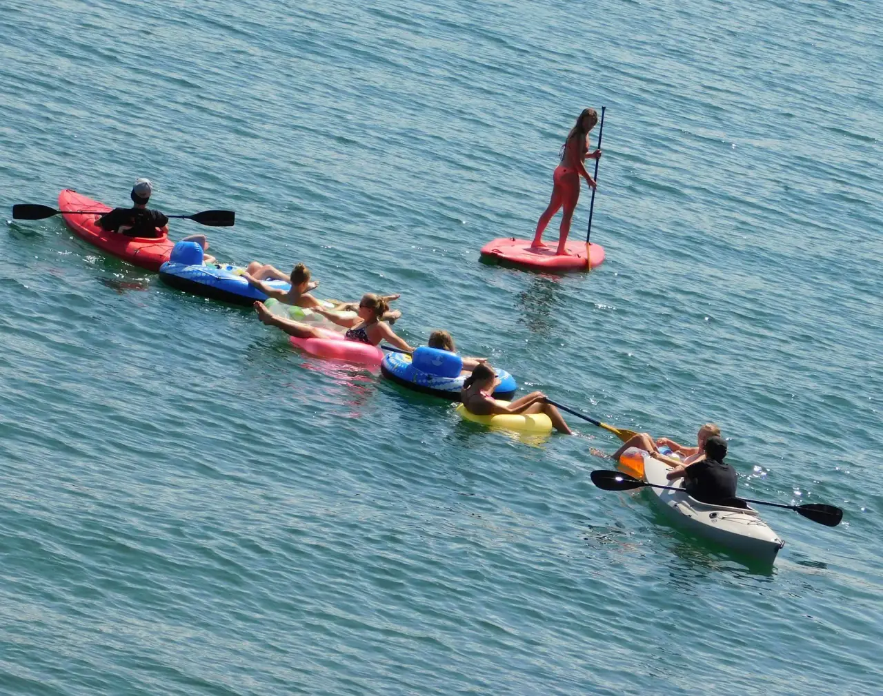 Ein Gruppenpaddel-Kajak und ein Paddleboard neben schwimmenden Schwimmern