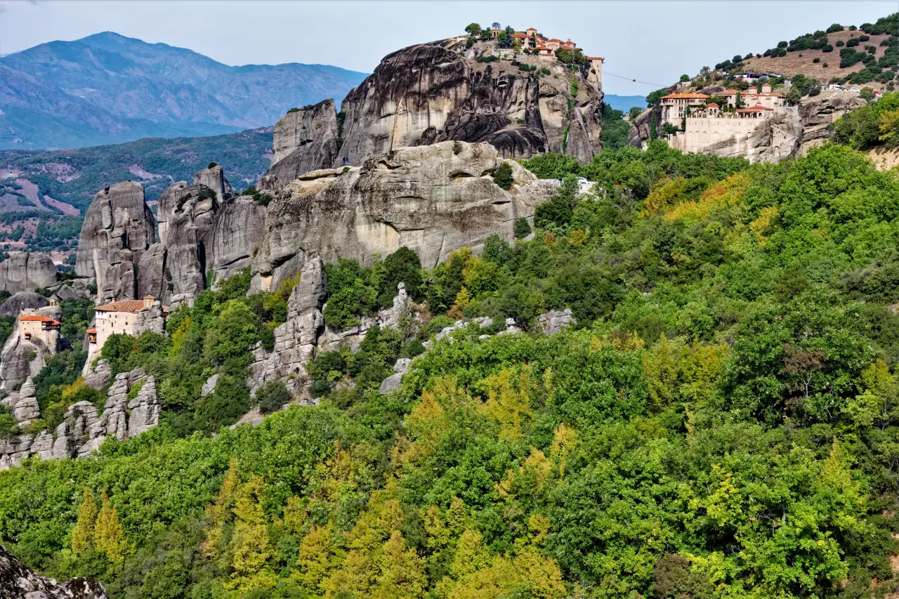 Monasterios iluminados por el sol sobre las escarpadas formaciones rocosas de Meteora, por encima de un bosque verde en Grecia.