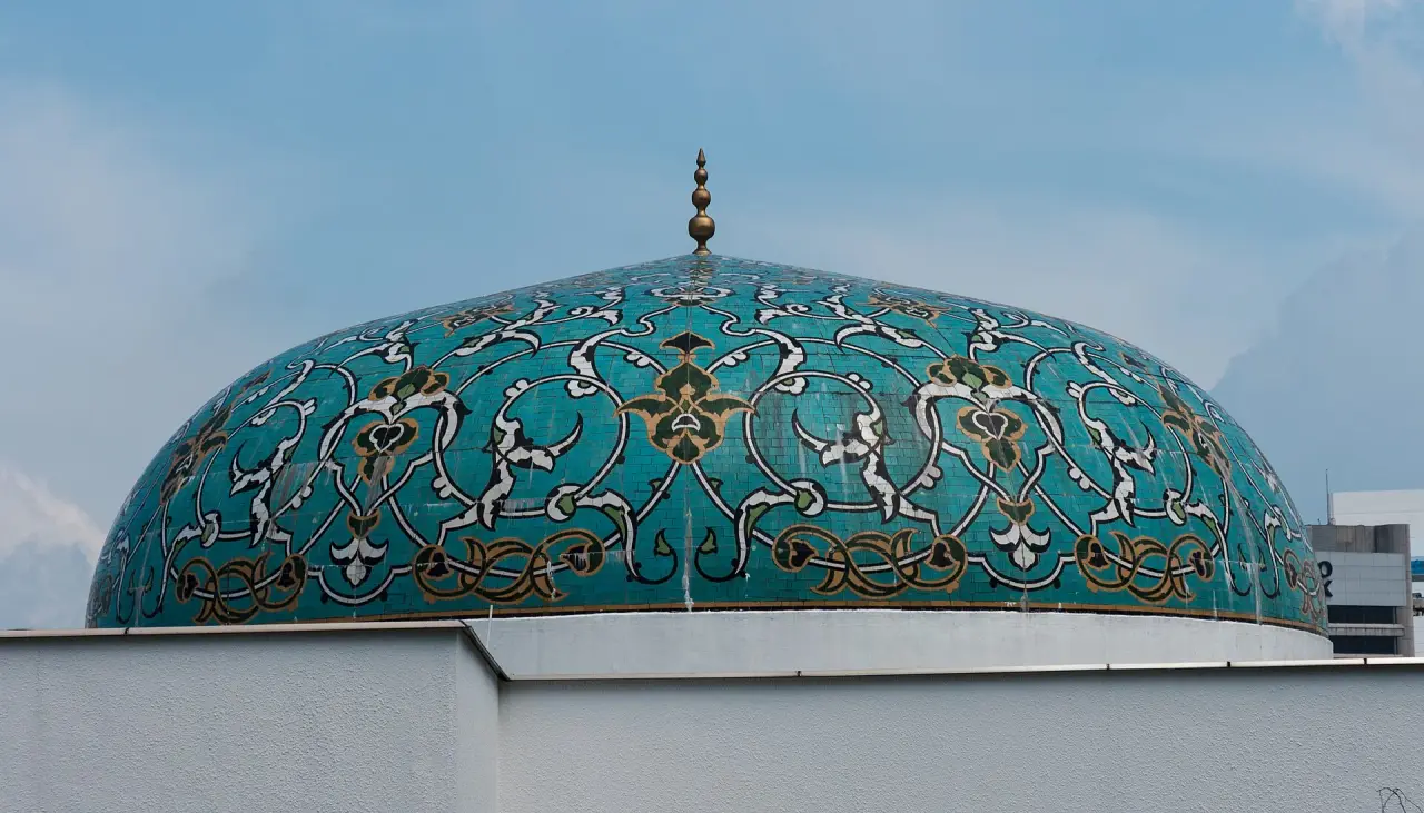 The complete turquoise patterned dome and finial of Islamic Arts Museum Malaysia against a blue sky