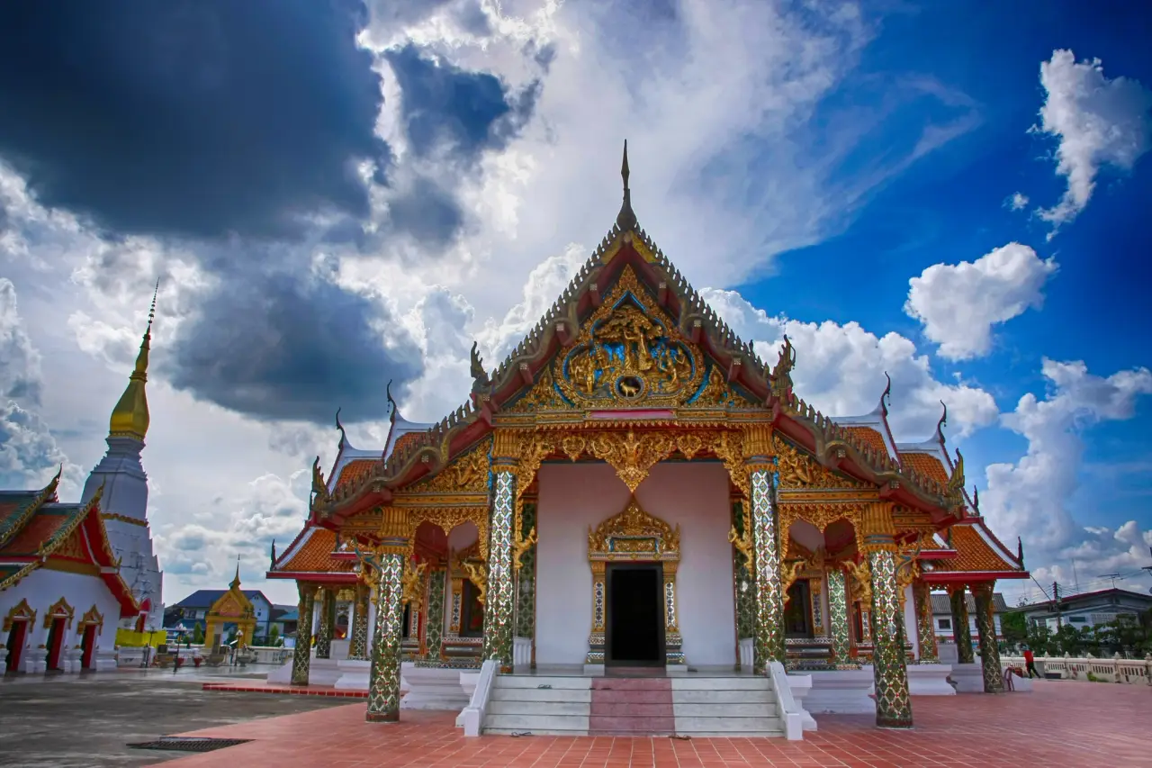 Decorated temple hall and white Phra That Choeng Chum stupa in Sakon Nakhon