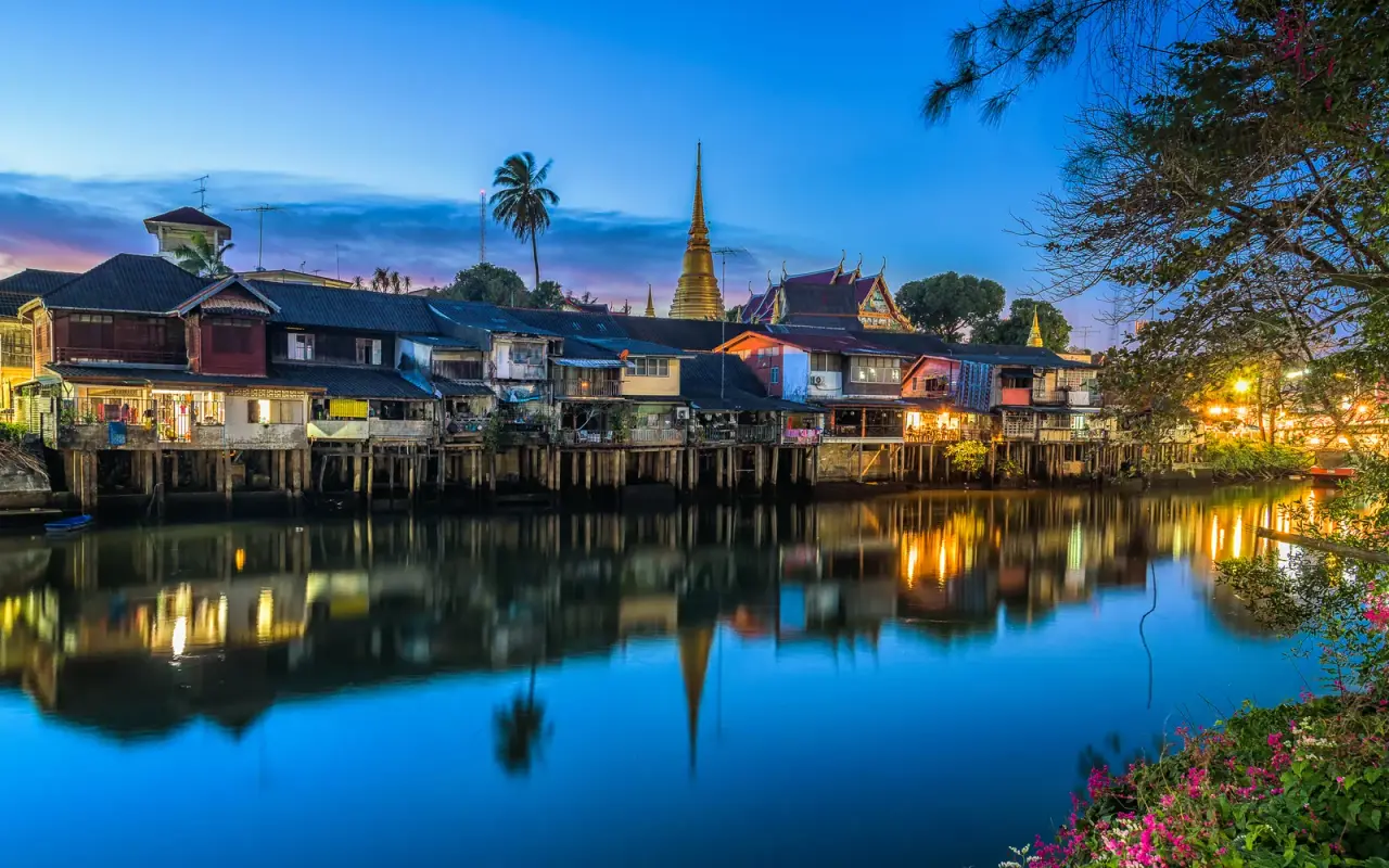 Colourful riverside houses reflected in the water at dusk in Chanthaburi