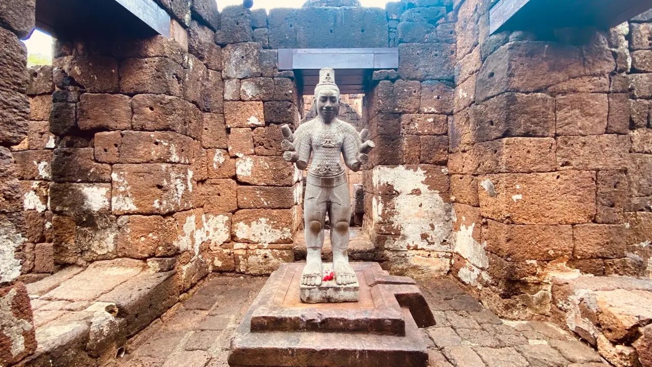 Buddhist sculpture framed by warm laterite sanctuary walls at Mueang Sing Historical Park