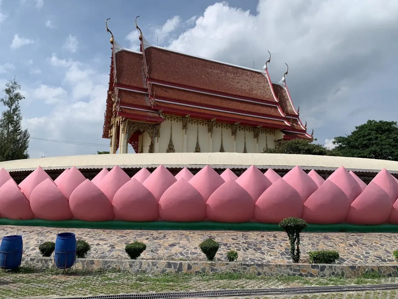 Red-roofed ubosot behind pink lotus-petal walls at Wat Muang in Ang Thong