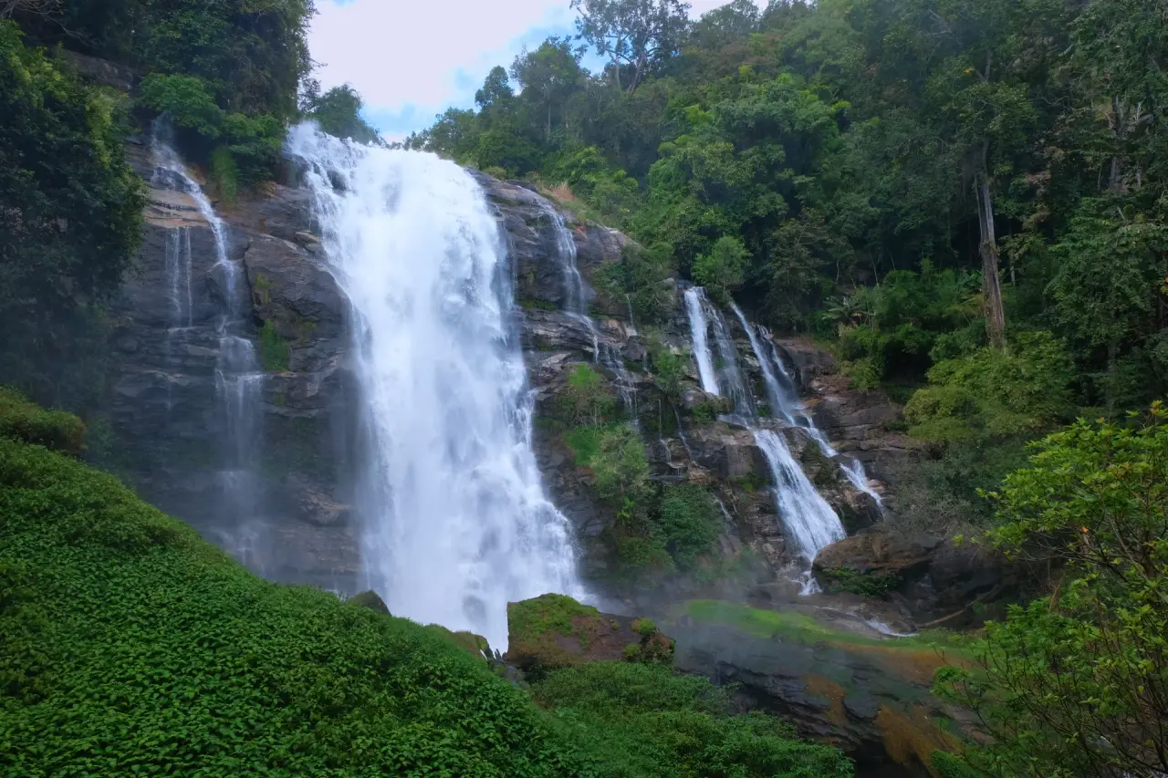 The complete main cascade and forested rock face at Wachirathan Waterfall