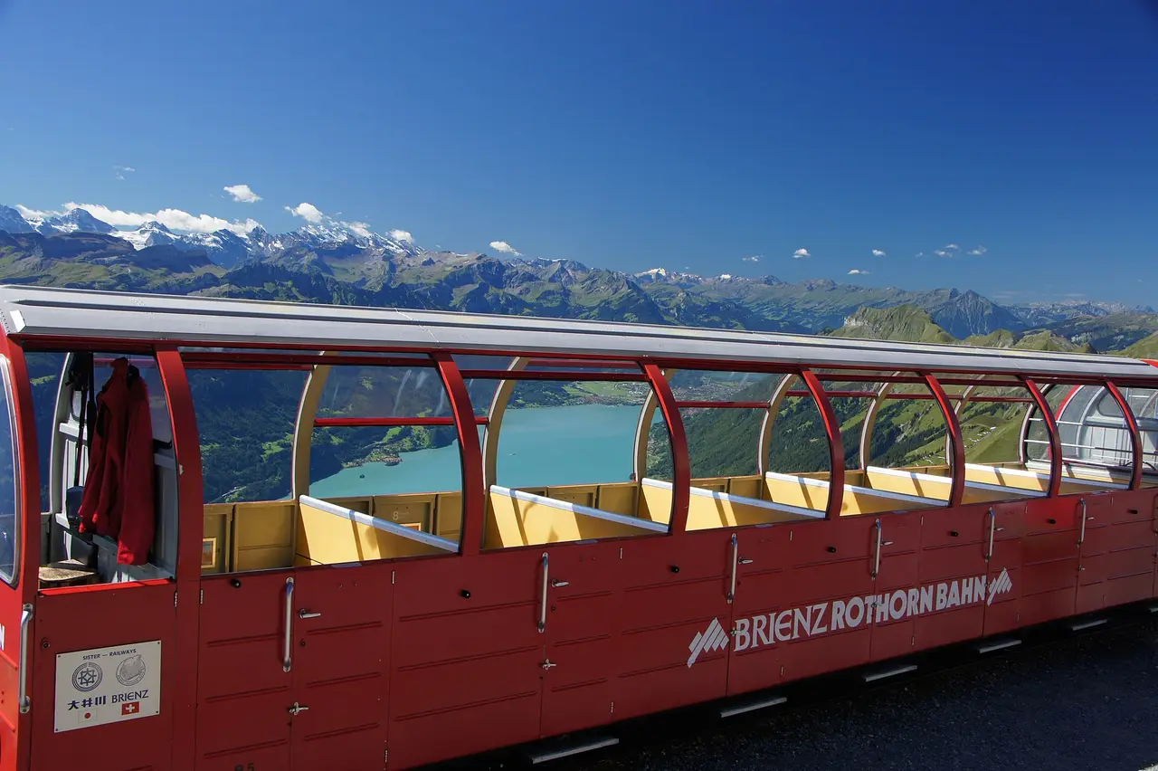 Red passenger carriage on the Brienz Rothorn Railway above Lake Brienz and the Swiss Alps
