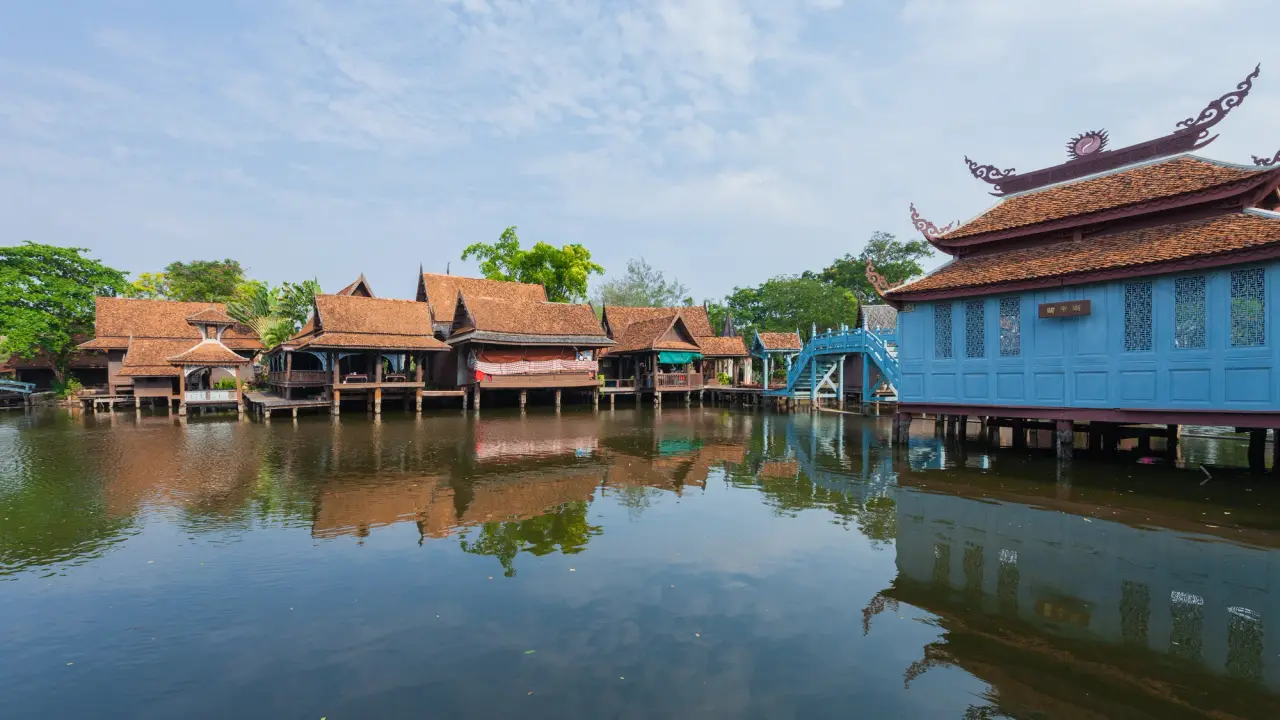 Traditional timber buildings reflected in the water at Ancient City’s floating-market zone in Samut Prakan
