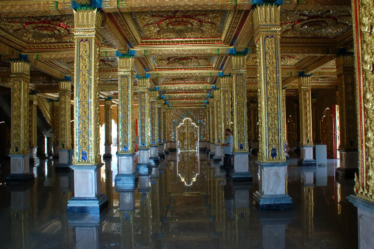 Vergoldete Spiegelsäulen und ein spiegelnder Boden im Glashalleninneren von Wat Tha Sung in Uthai Thani.