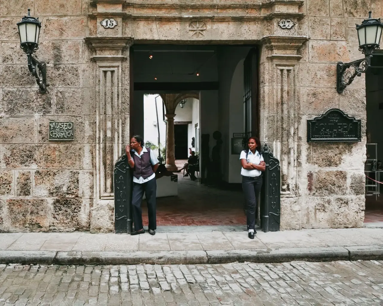 Deux agents de part et d’autre de l’entrée historique d’un musée et de son seuil en pierre.