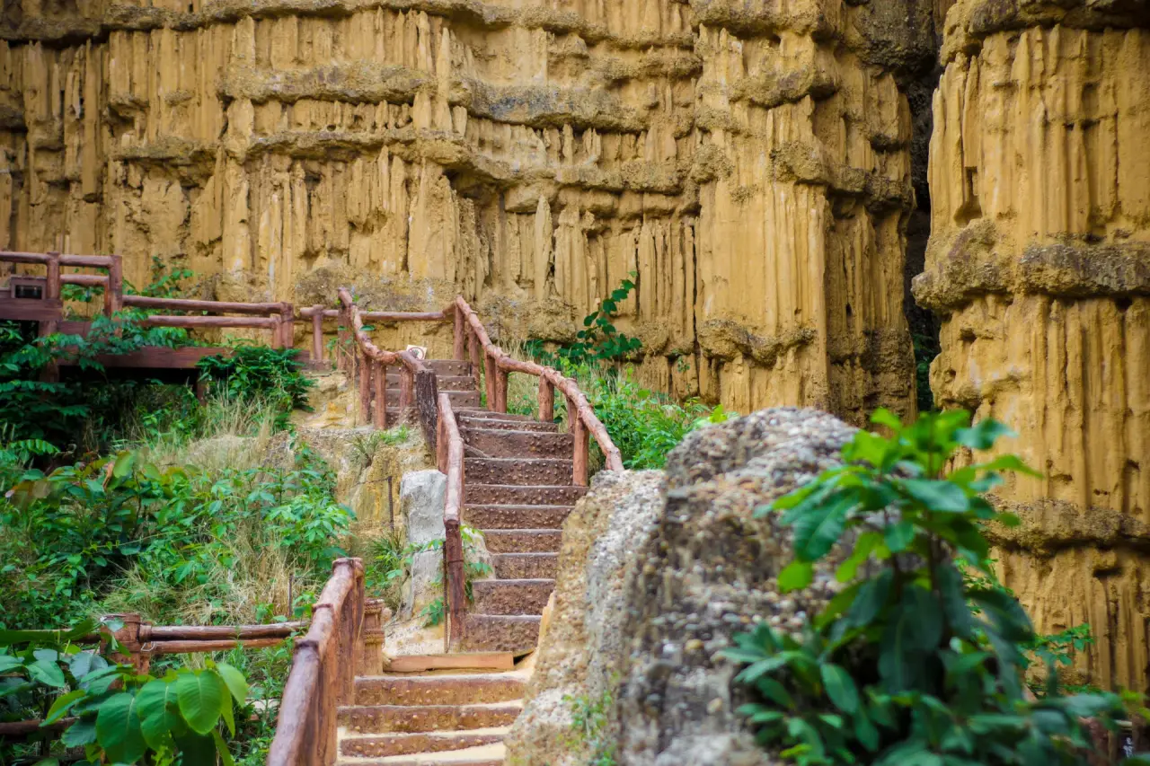 Besuchertreppe unter den ockerfarbenen Sedimentwänden von Pha Chor im Mae Wang Nationalpark