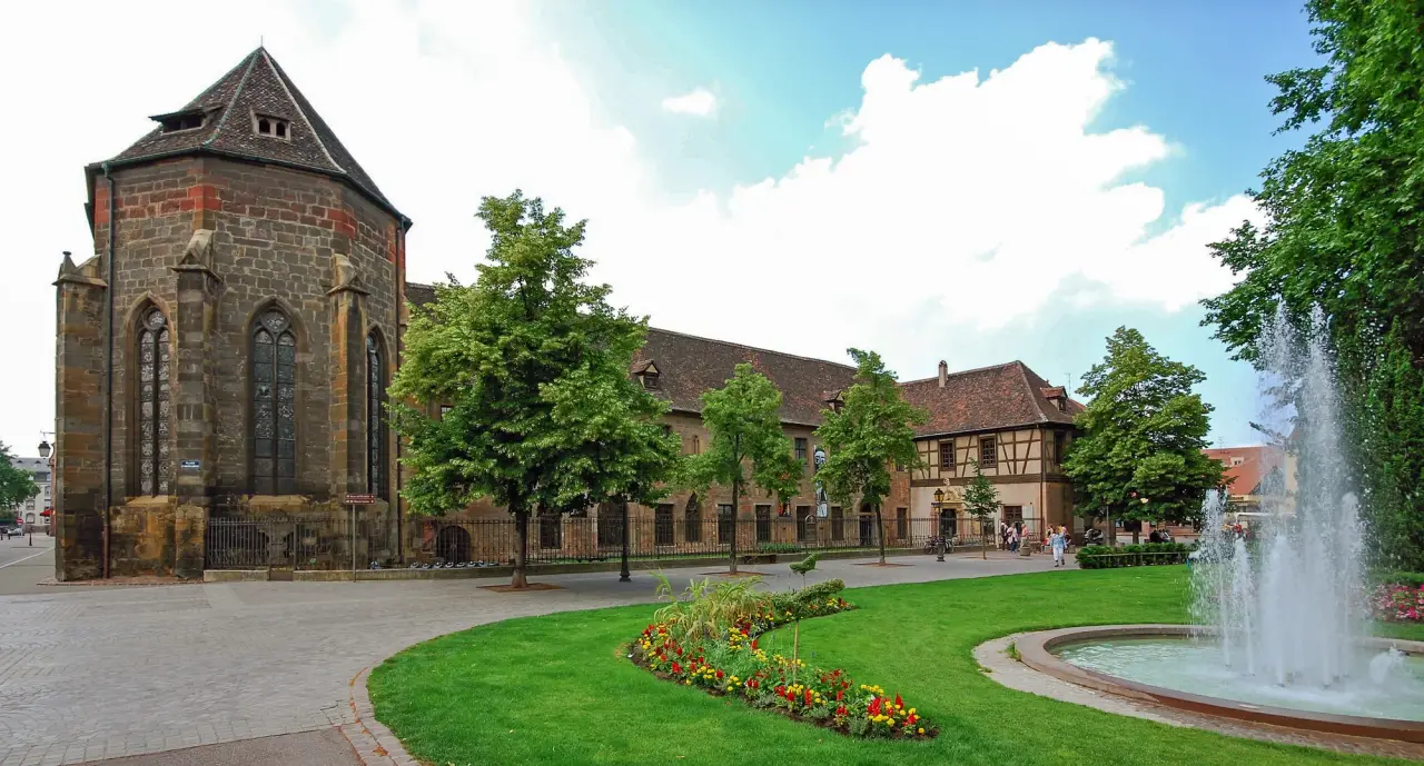 The historic Unterlinden Museum buildings beside a planted garden and fountain in Colmar