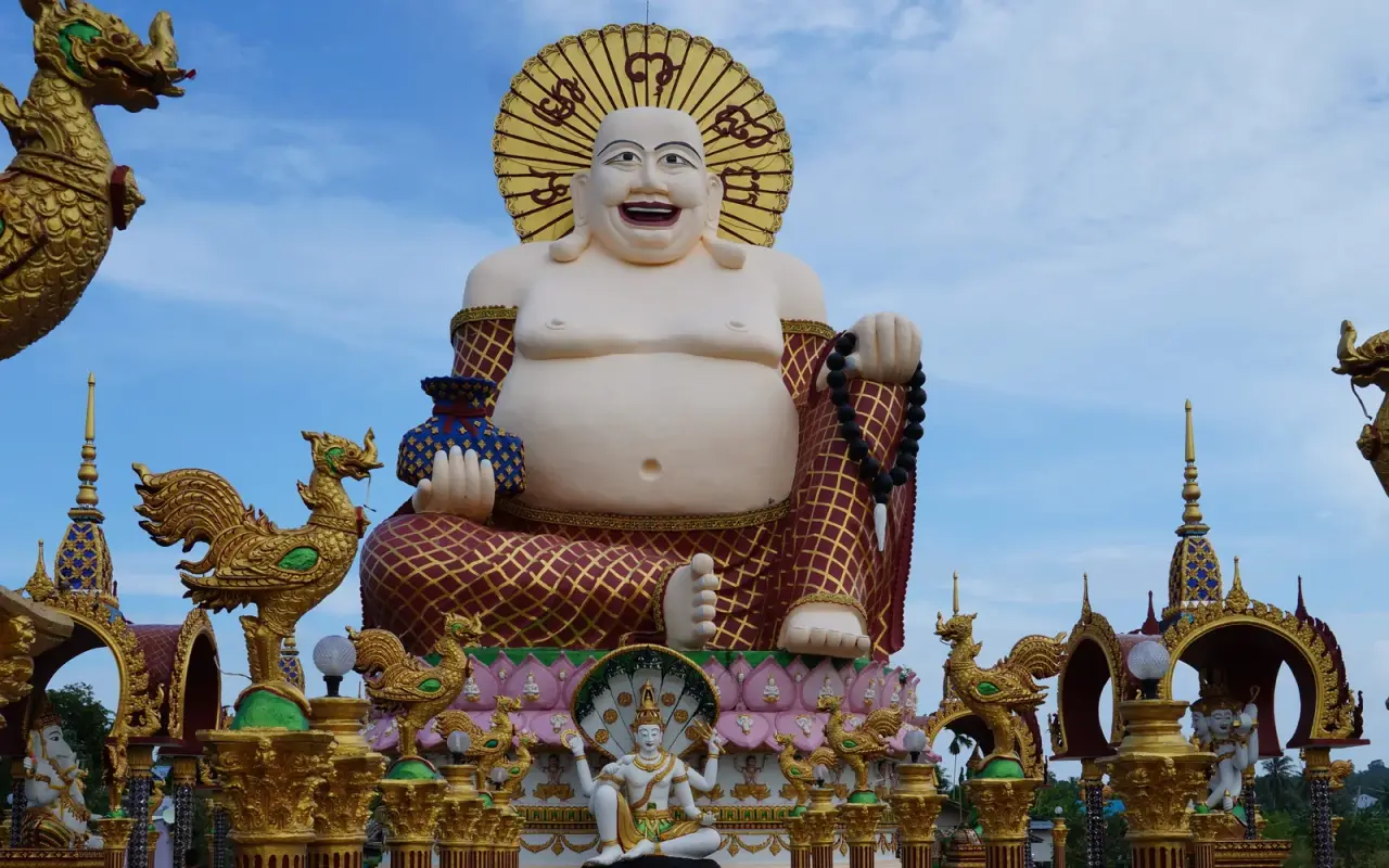 The colourful Budai statue at Wat Plai Laem on Koh Samui under a blue sky