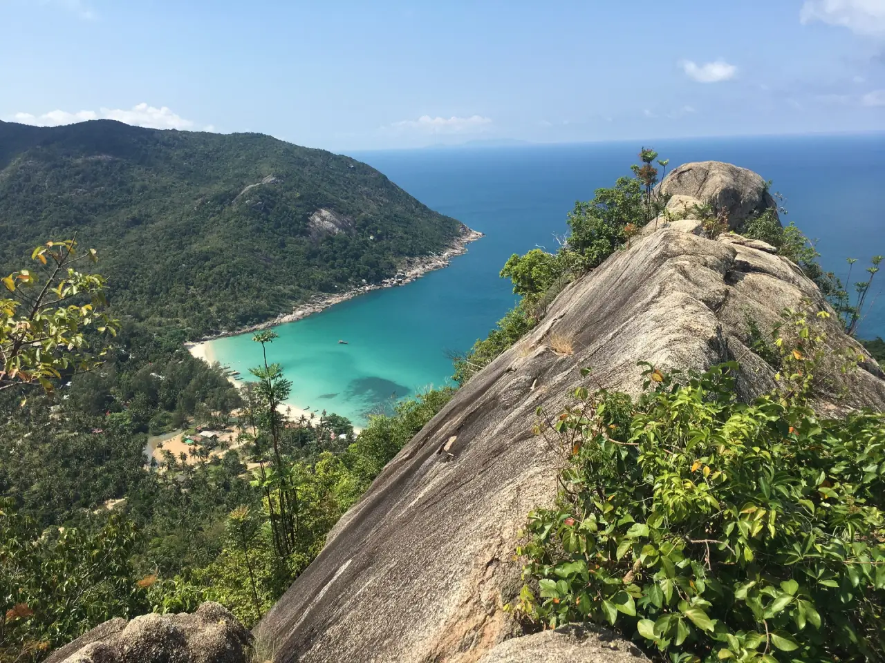 Turquoise Bottle Beach below a forested Koh Phangan hillside and rocky viewpoint.