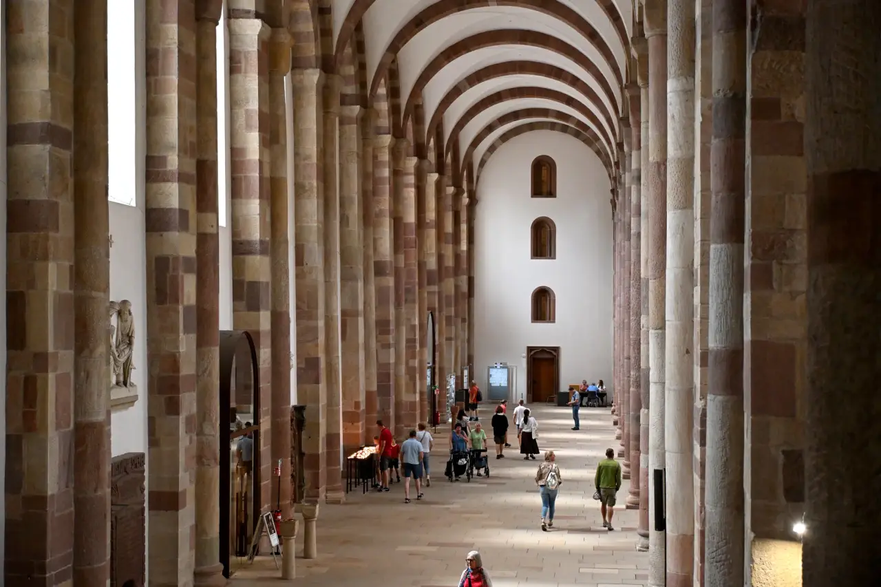 Visitors beneath the repeated Romanesque arches of the south aisle at Speyer Cathedral