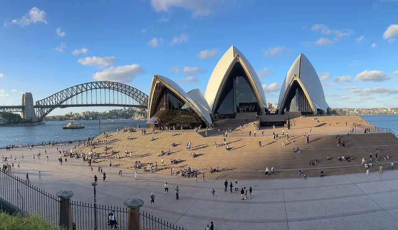 The Sydney Opera House beside its public steps, with the harbour and Harbour Bridge beyond.