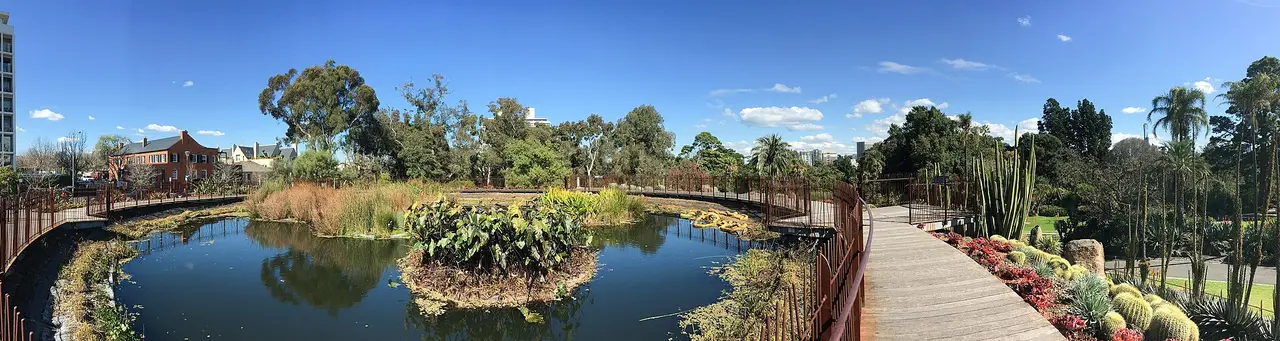 El embalse del volcán Guilfoyle con plantación tolerante a la sequía y cielo azul en Melbourne Gardens