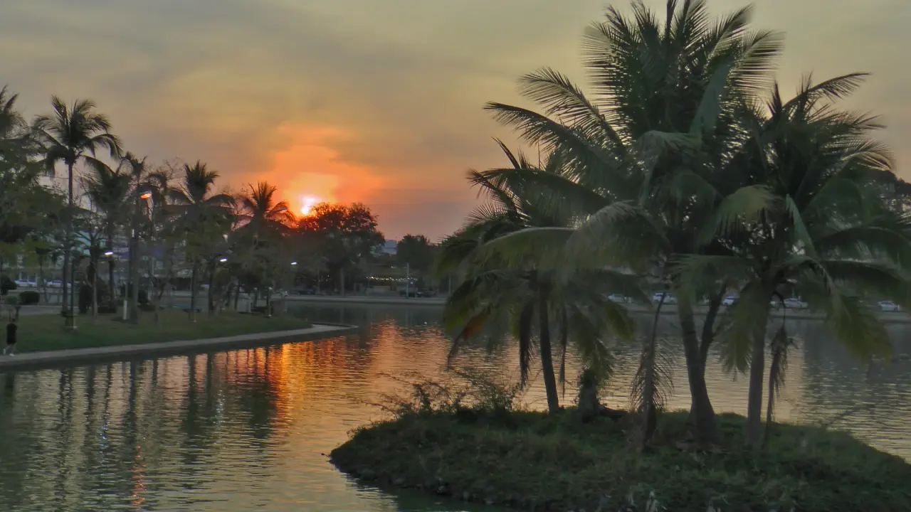 Palm trees and warm sunset reflected in Bueng Phalan Chai lake in Roi Et