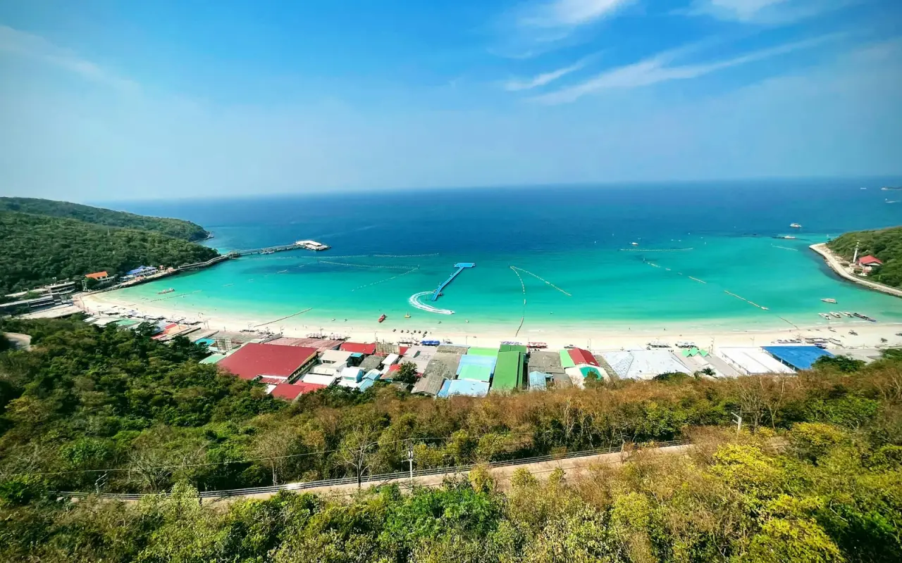 A white sandy beach and turquoise bay on Koh Larn viewed from a green hillside