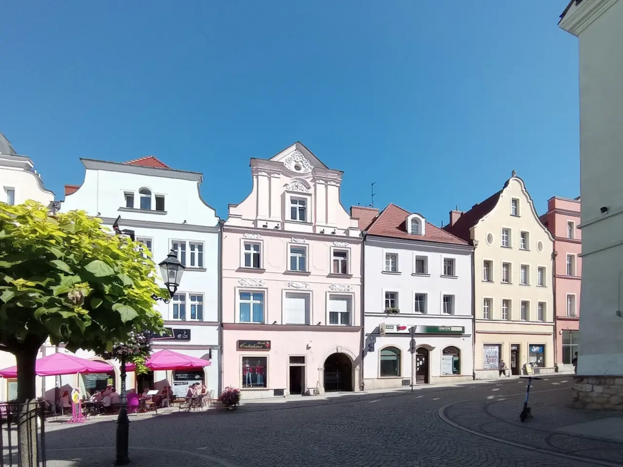 Pastel historic façades around the market square in Bolesławiec beneath a clear blue sky