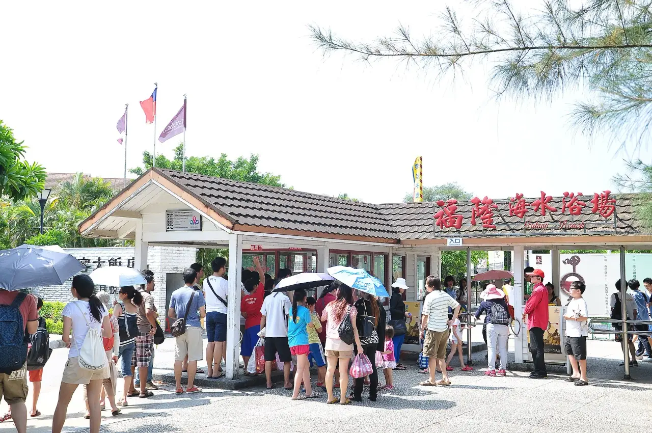 Visitors queue beneath umbrellas at the Fulong Beach ticket entrance in Taiwan