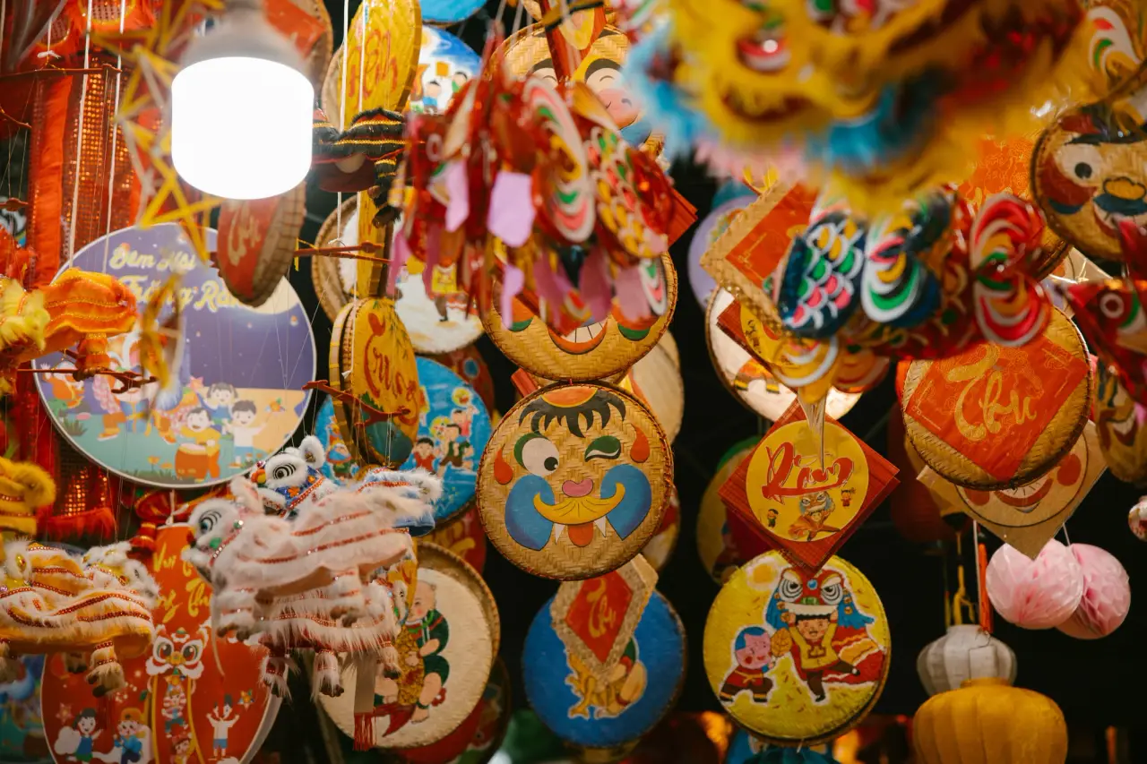 Las coloridas decoraciones del Festival de Medio Otoño vietnamita y las pequeñas cabezas de león llenan una exhibición de mercado brillantemente iluminada.
