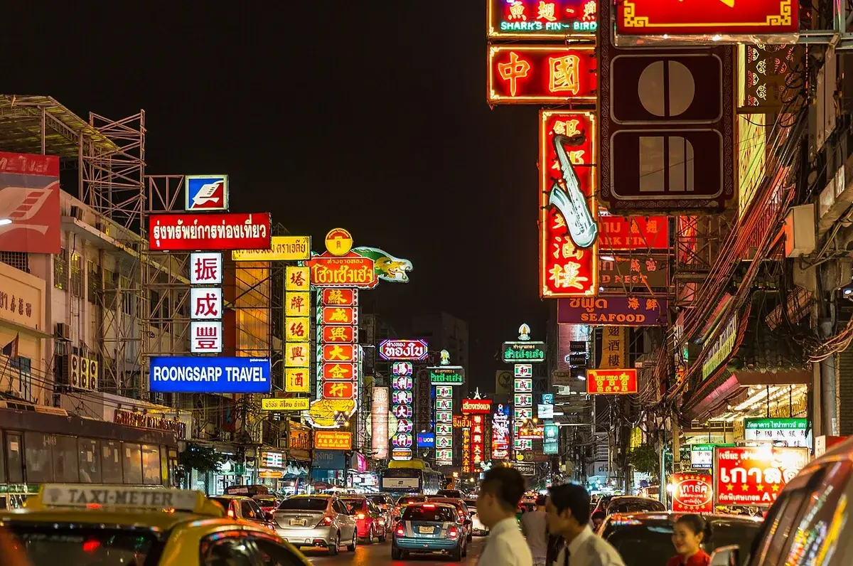 Letreros de tiendas iluminadas a lo largo de Yaowarat Road en Bangkok Chinatown por la noche