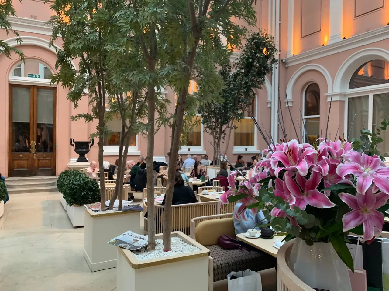 Des convives parmi les arbres et les fleurs roses dans la cour couverte de la Wallace Collection, à Londres.