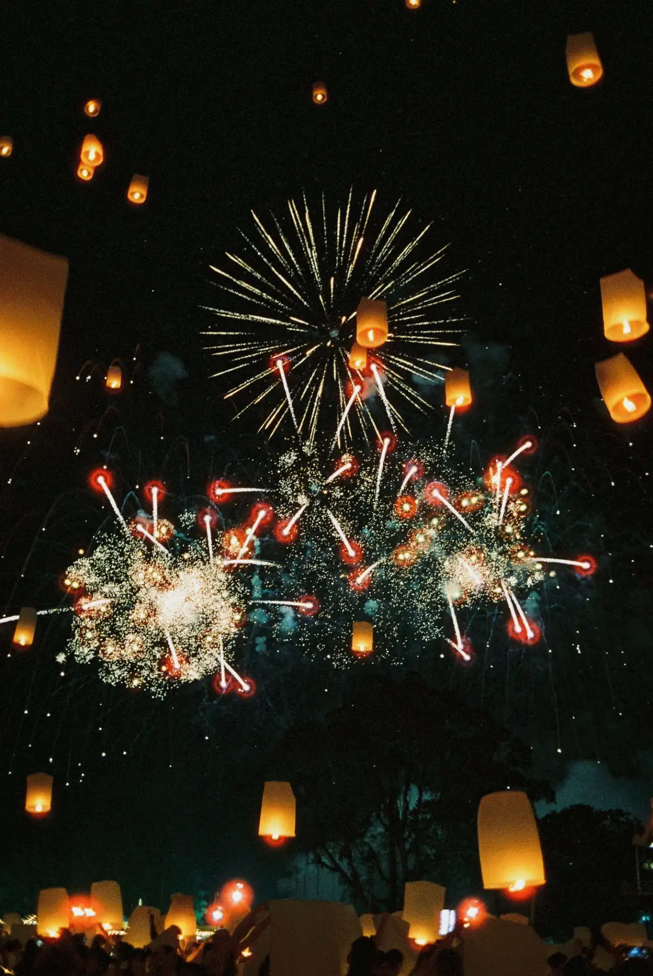Sky lanterns and bright fireworks fill the night sky at a festival in Chiang Mai.