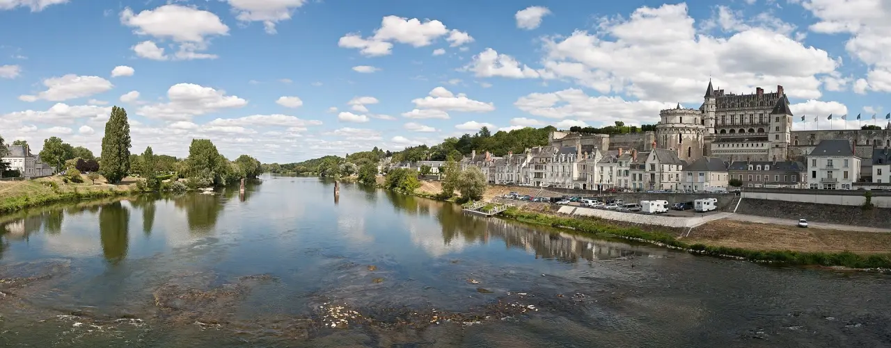 The Loire River reflecting the riverside buildings and château at Amboise in bright summer daylight