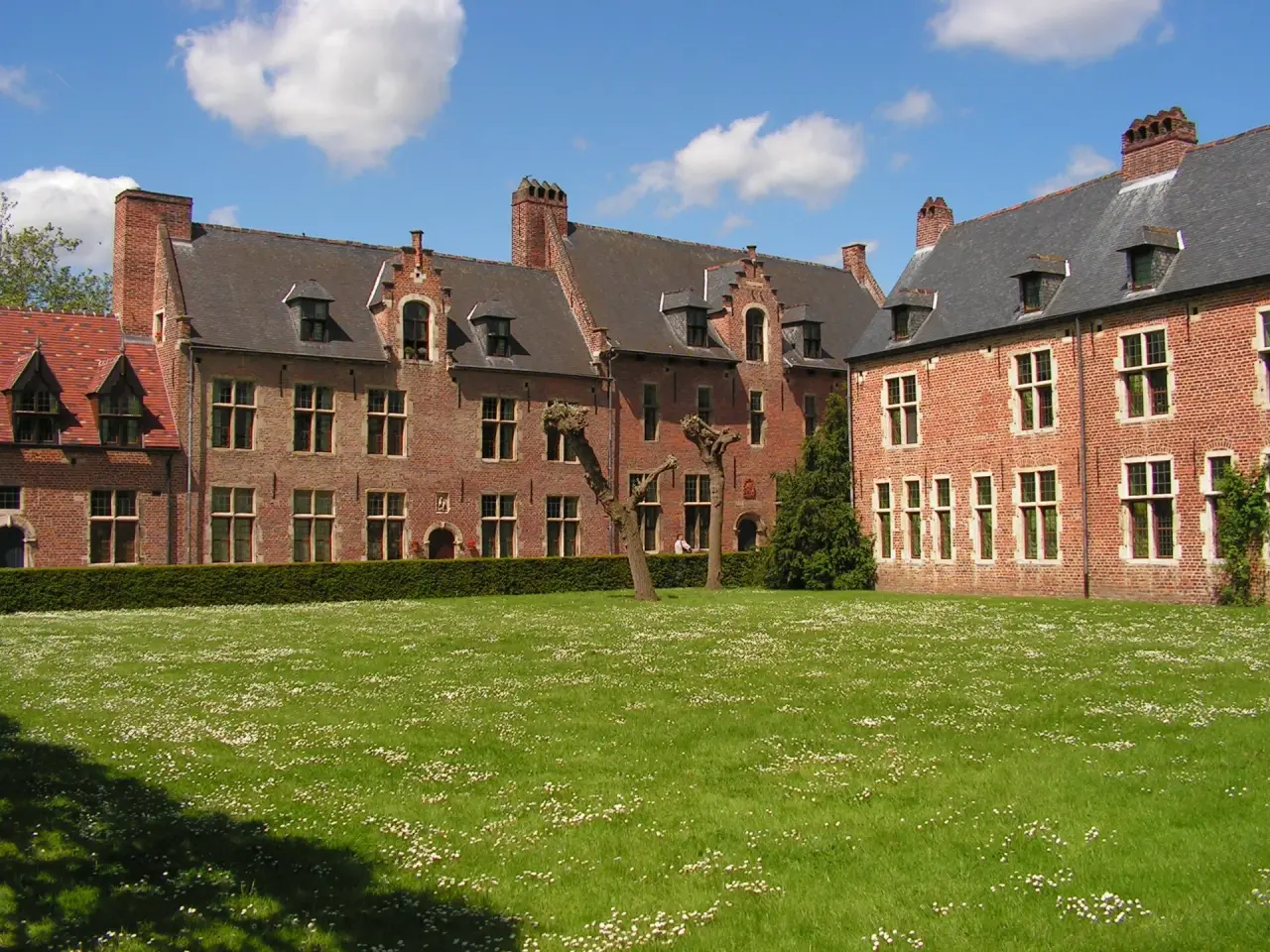 Historic brick houses and a green lawn in Leuven’s Great Beguinage