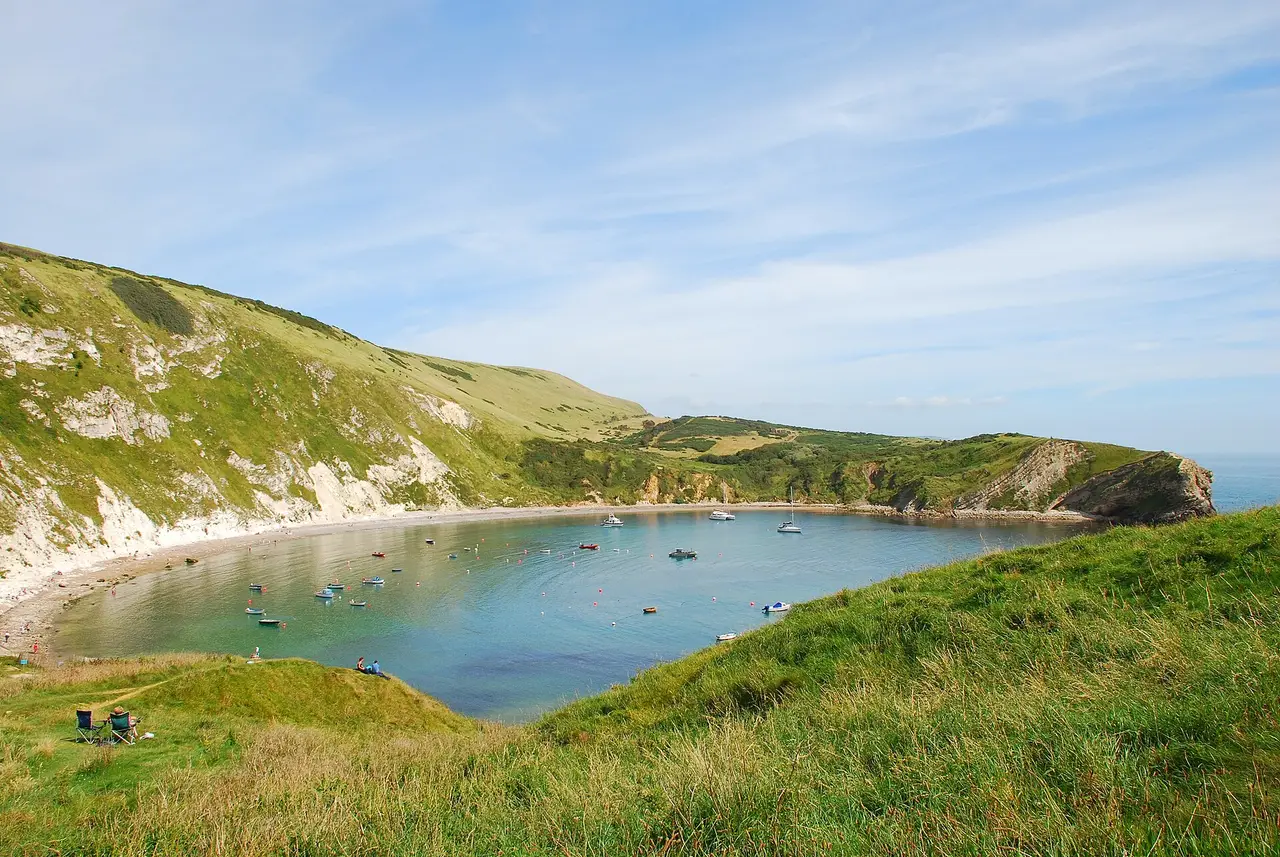 Green hills and pale coastal rock surrounding Lulworth Cove in Dorset