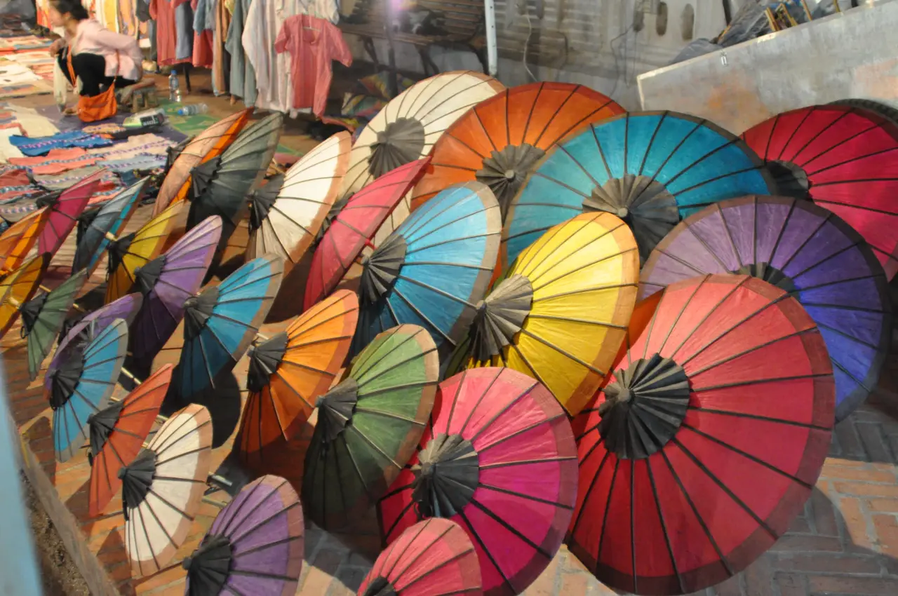 ร่มกระดาษหลากสีจัดแสดงข้างแผงขายของที่ตลาดกลางคืนหลวงพระบาง ประเทศลาว