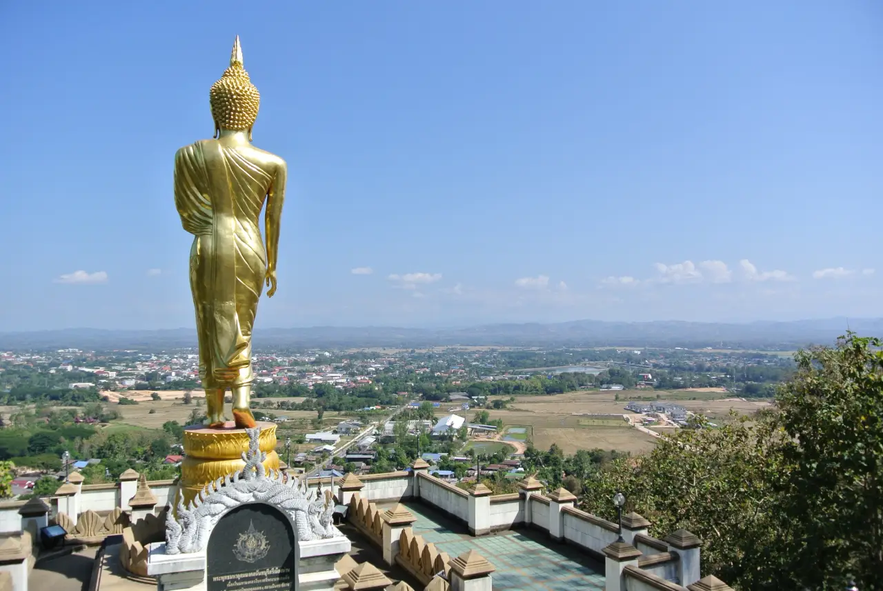 A standing golden Buddha seen from behind above the Nan valley at Wat Phra That Khao Noi.