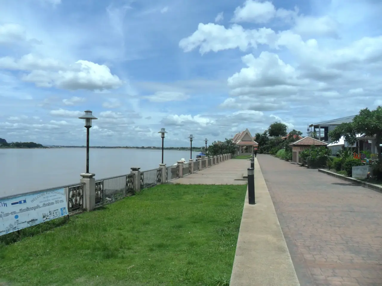 The paved Mekong riverfront promenade in Nong Khai, with lamps, a riverside pavilion and the Lao bank across the water.
