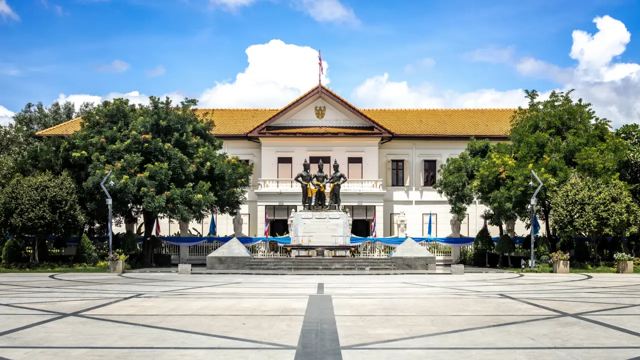 The Three Kings Monument stands before the central white facade and gold roof of Chiang Mai City Arts and Cultural Centre.