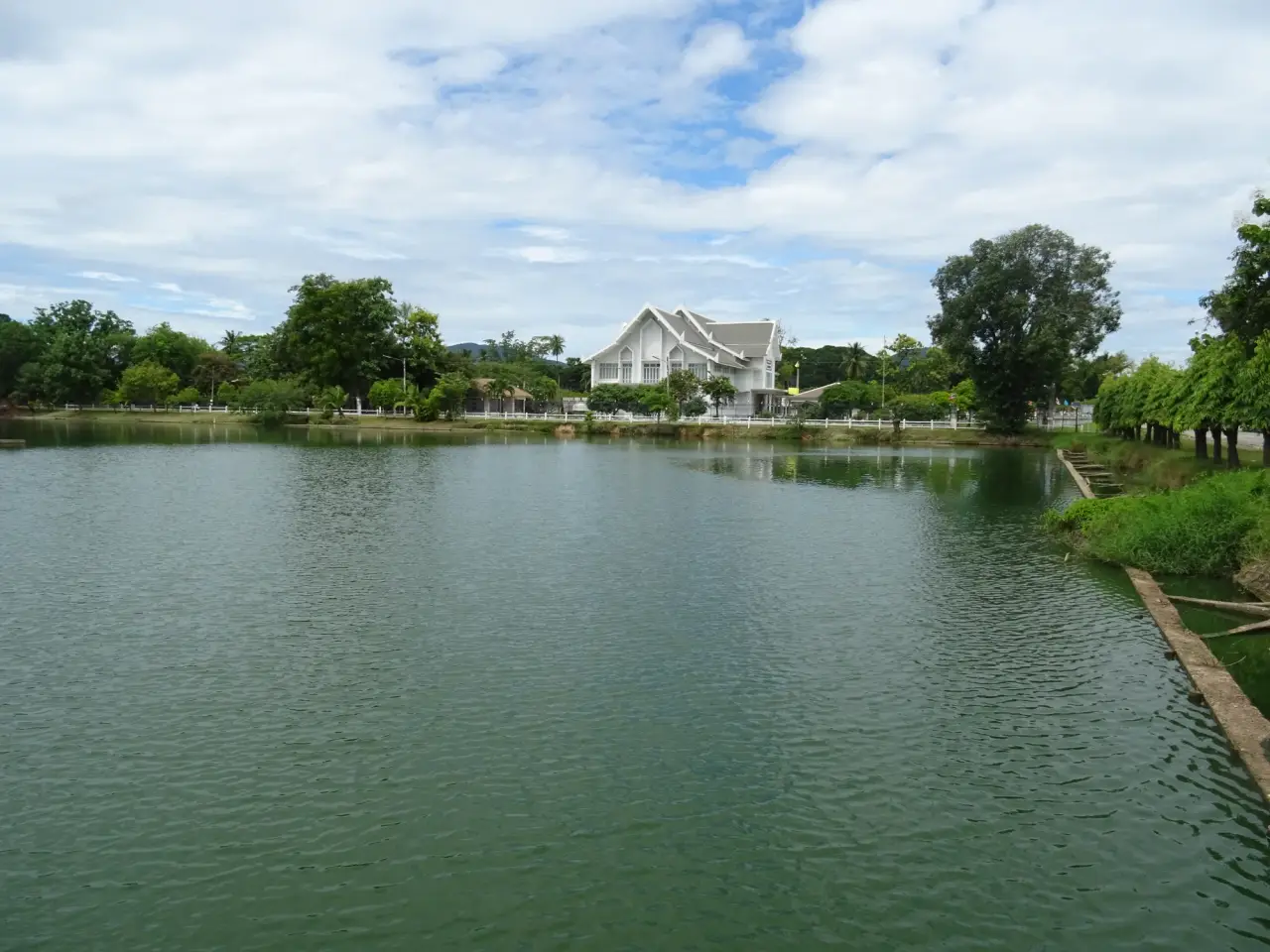 Ramkhamhaeng National Museum in Sukhothai seen across its pond, with its white Thai-style facade and trees.