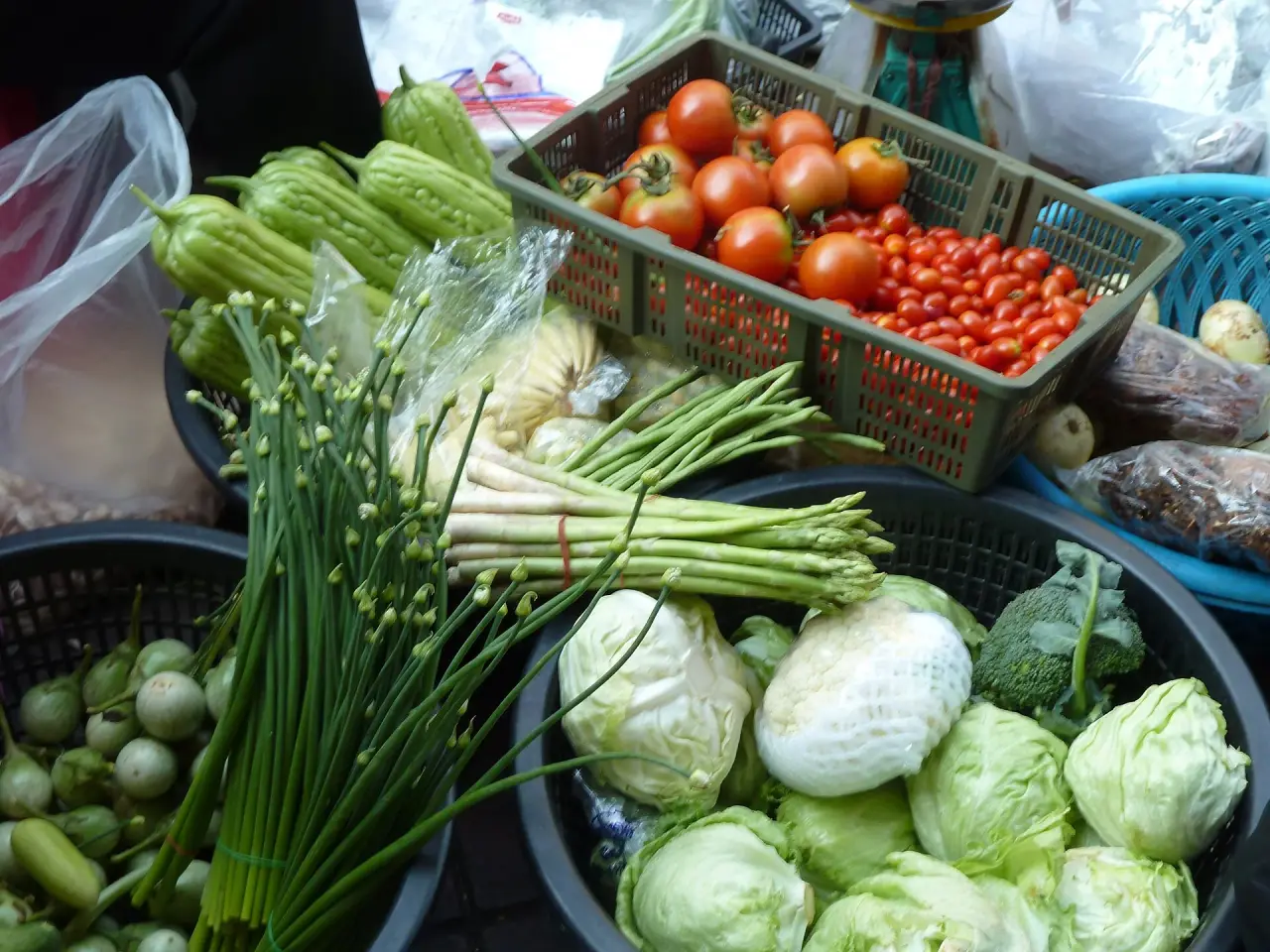 Baskets of green vegetables and tomatoes at a Bangkok market